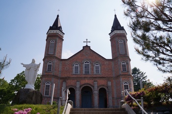 빨간 벽돌과 두 개의 첨탑을 갖고 1929년에 준공된 성당 외부.