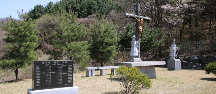 성지 정면에 야외제대와 대형십자가, 그 좌우로 성 김대건 안드레아 신부상과 최양업 토마스 신부상이 서 있다.