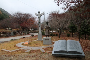 성지 입구에 건립된 한국교회 최초의 수덕자 홍유한 선생 동상과 십자가.